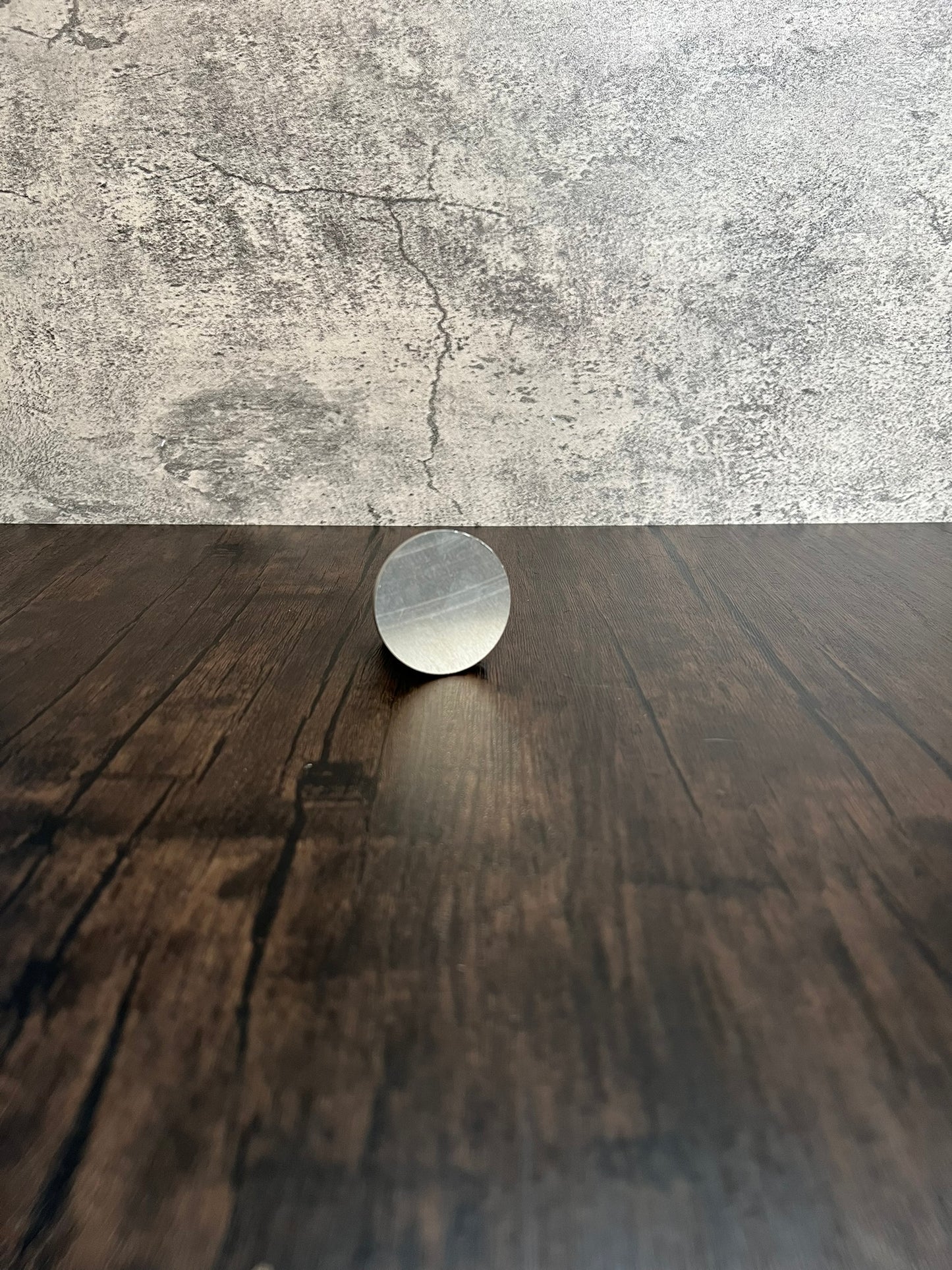 small round metal disc on wood and stone background