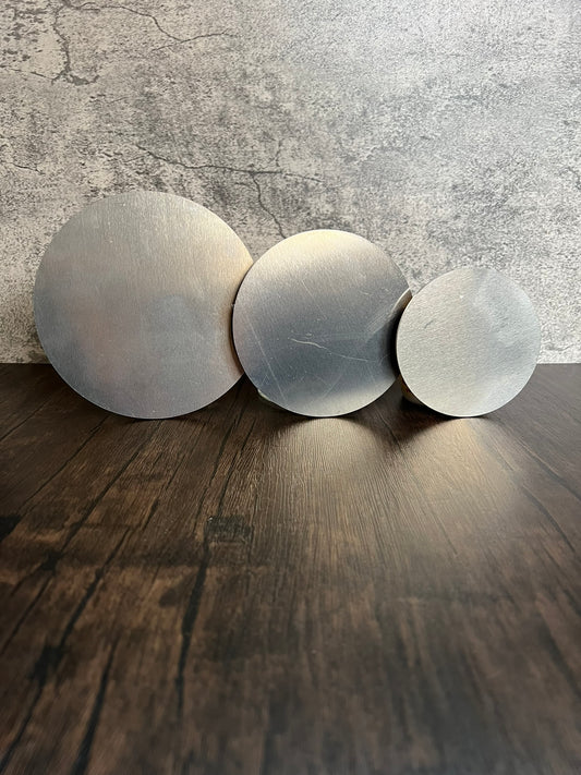 three different sizes of round metal discs on wood and stone background