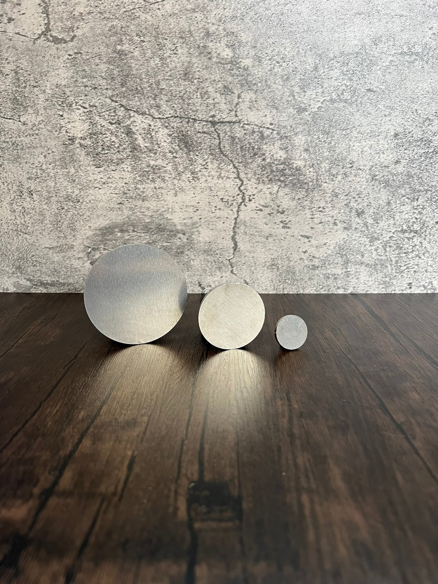 three different sizes of round metal discs on wood and stone background